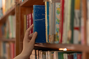 hand removing a book from a library shelf